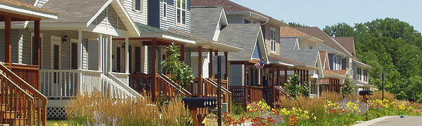Looking down the street, several homes of different types, with red and yellow flowers planted along the parking.