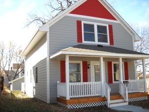 A gray Habitat home with red trim.
