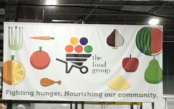 The Food Group's banner, which includes the logo, as well as illustrations of fruits and vegetables against a white background, and the words "Fighting hunger. Nourishing our community."