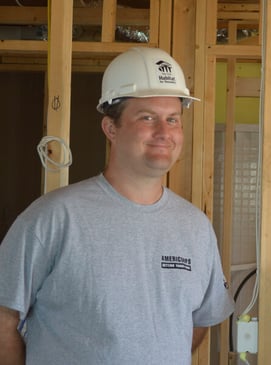 Habitat AmeriCorps Member Mickey Foley leaning against the frame of a house.