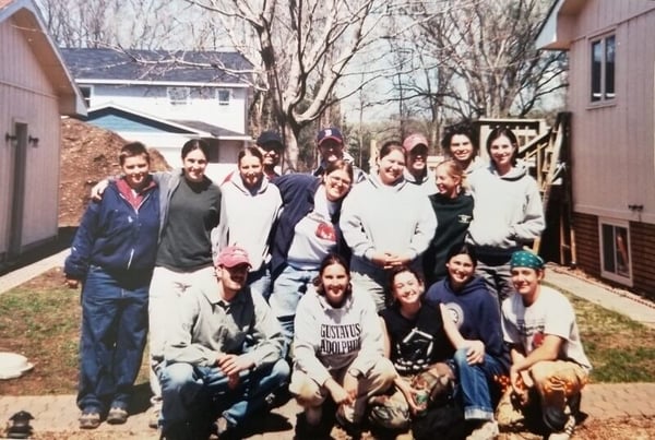 Heather's 2003 AmeriCorps cohort posing between two houses outsdie.