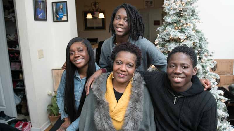 Melo with family in front of a holiday tree.