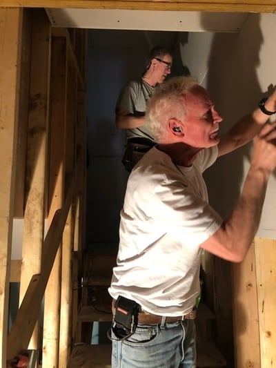 Two Third Act volunteers working on a wall while standing in a stairwell.