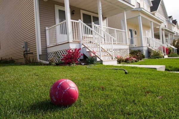 A beige house with a front yard. A red soccer ball sits on the front yard.
