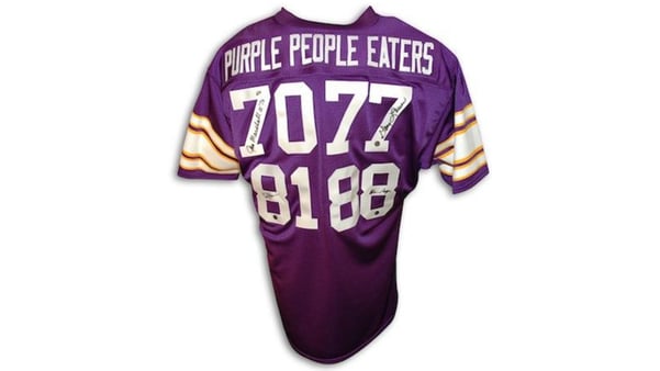 A purple Vikings jersey that says "Purple People Eaters" on the back, with the numbers 70, 77, 81, and 88 below it. Each number is signed by the player who wears that number, listed below.