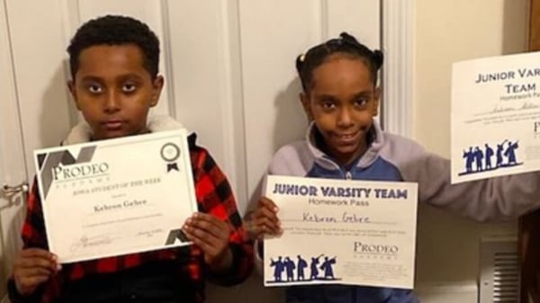 Samuel's two kids holding three different award certificates.