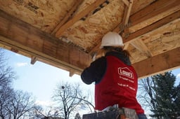 A volunteer in a Lowe's vest, working on a roof.