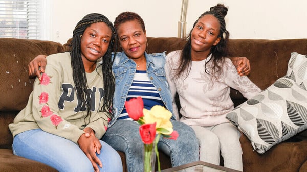 A Habitat homeowner with her two daughters on their couch.