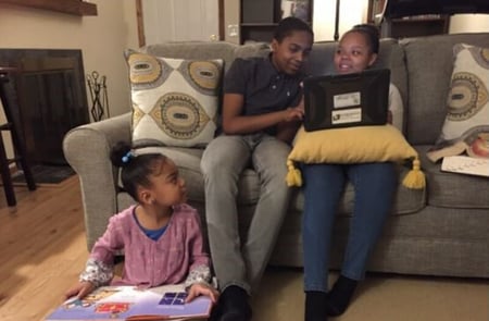 Angel's son Don helping his sisters with homework in their living room.