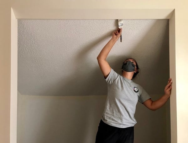 Maddie painting a doorframe in a Habitat home.