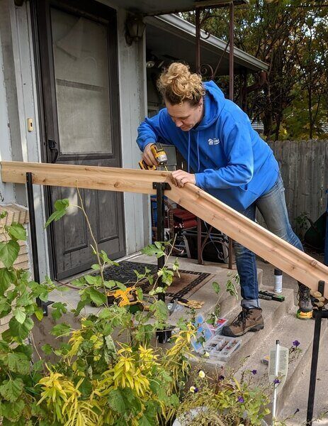 Ashley installing a railing on the front steps of a home.