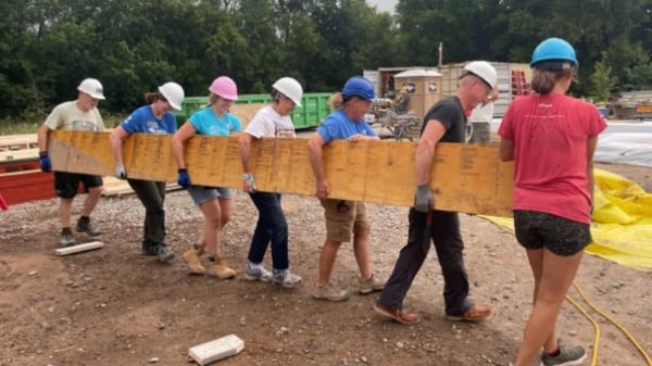 Volunteers lifting a beam.