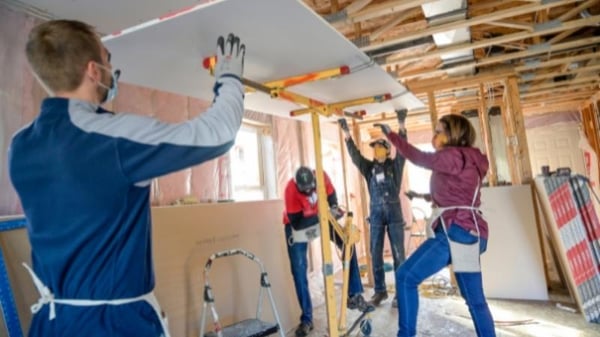 Volunteers lifting drywall.