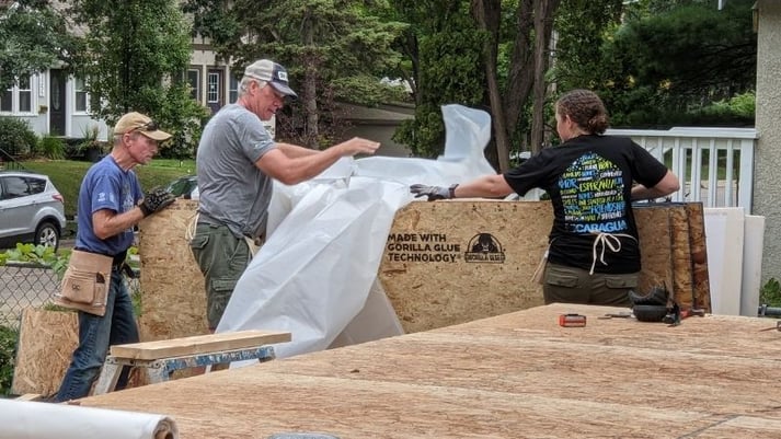 Chris Coleman and Global Village volunteers cover water-sensitive building materials before one of the many rain showers during the build.