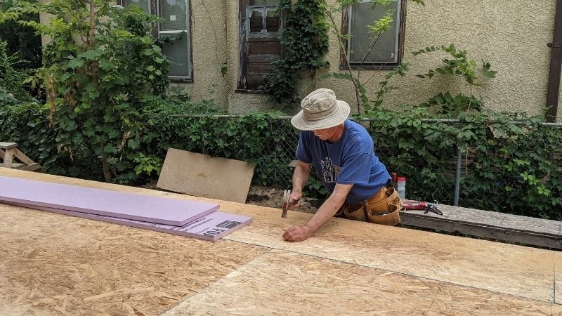 John DeWolf pounds nails at the GV Gone Local build site, fastening subfloor onto first floor trusses.