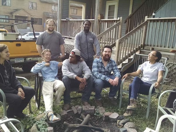 AmeriCorps members gather around a backyard fire pit.