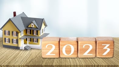 Miniature wooden house next to wood blocks that say 2023.
