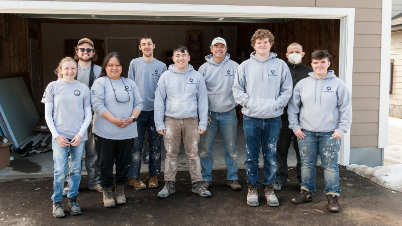 AmeriCorps members in a group photo in front of an open garage