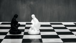 A chess board with black and white "thinking man" pieces.