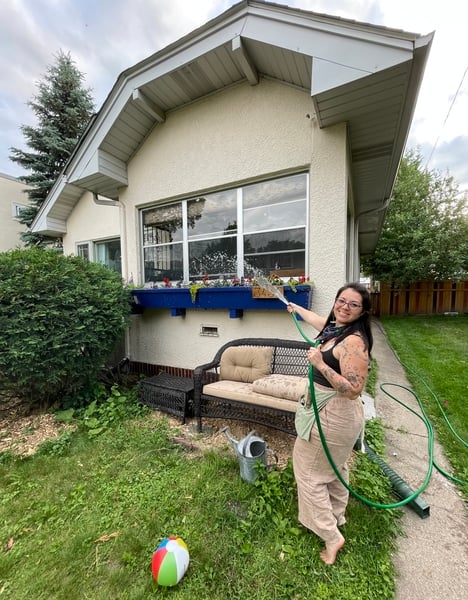 Camila watering flowers in her front yard.