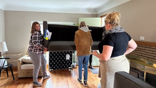 Four people moving a couching into a living room.