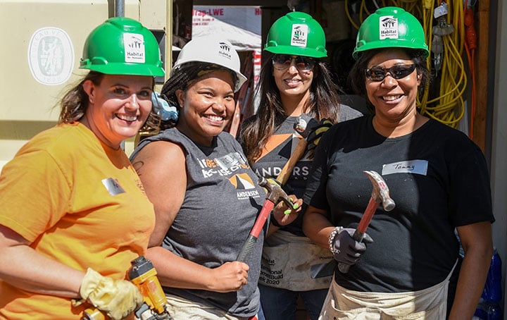 Four volunteers smiling and holding hammers