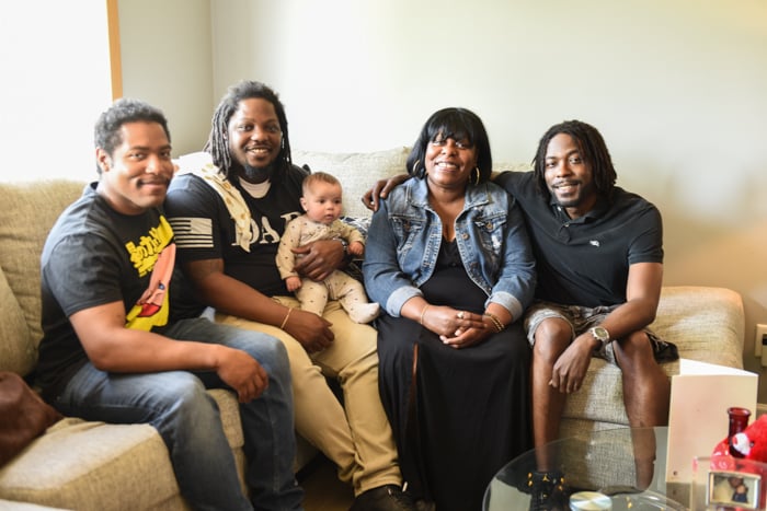 Habitat homeowner Angela and her three sons and one grandbaby sit on a couch together.