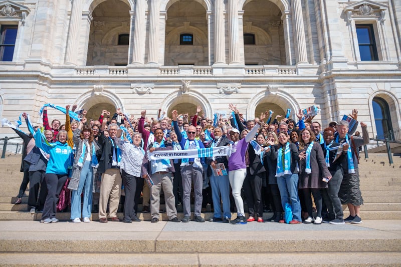 A large group of people cheering on the Minnesota Capitol steps.