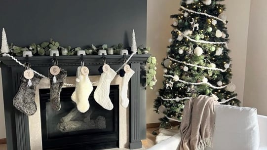 Minimalist and-made yarn stockings and Christmas ornaments in a living room.