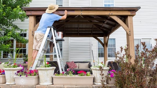 a person in a wide-brimmed hat working on a patio roof.