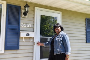Angela stands outside the front door of the home she bought with Habitat