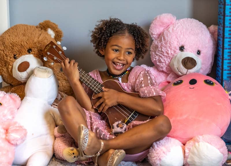 Carroll daughter Alexandria playing ukelele with stuffed animals