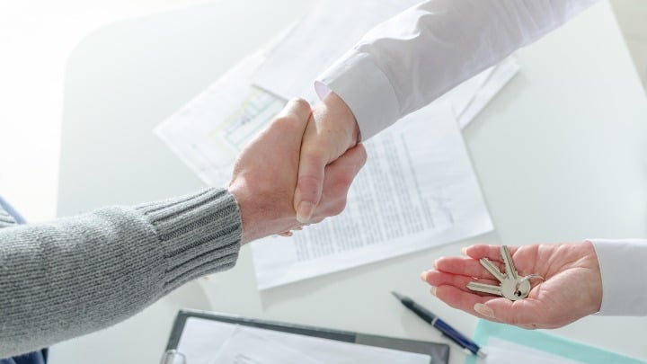 Close up of handshake over paperwork.