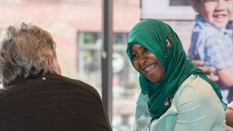 Homeowner in head covering laughing with a board member.