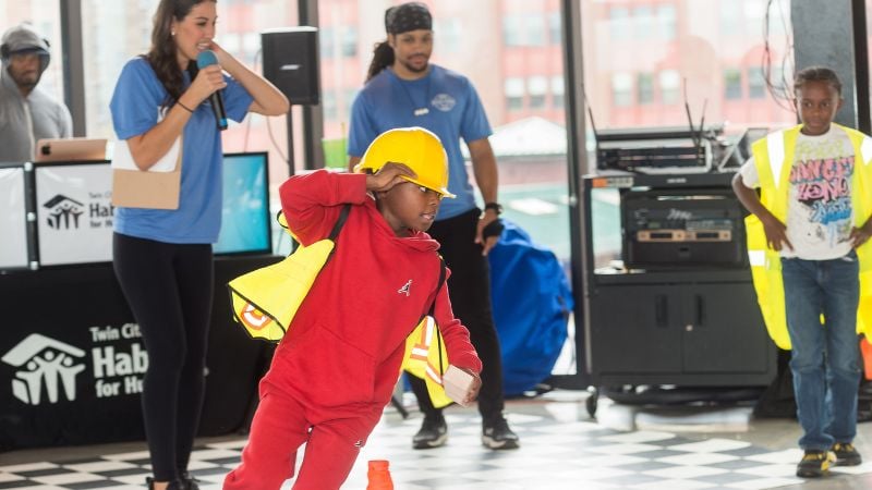 Kids competing in a relay race in construction-themed costumes.