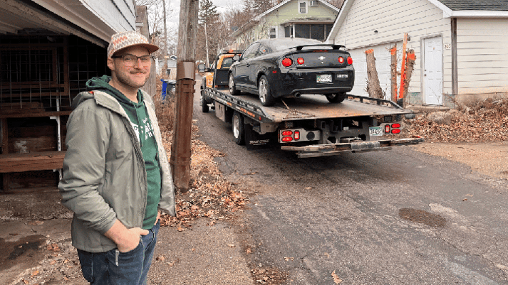 Greg watching as his car is towed away for Cars for Homes