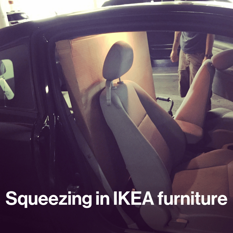 A large box narrowly fits in the backseat of a car