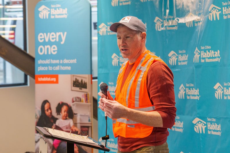 Andersen CEO Chris Galvin holding a microphone and speaking at a build event.