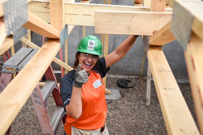 Construction volunteer pointing and smiling at the camera.