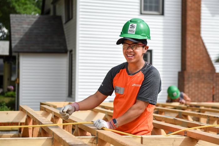 Construction volunteer measuring a beam.