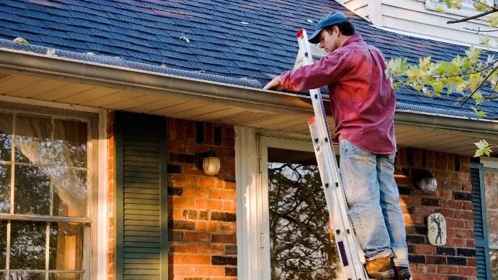 Homeowner cleaning a gutter.