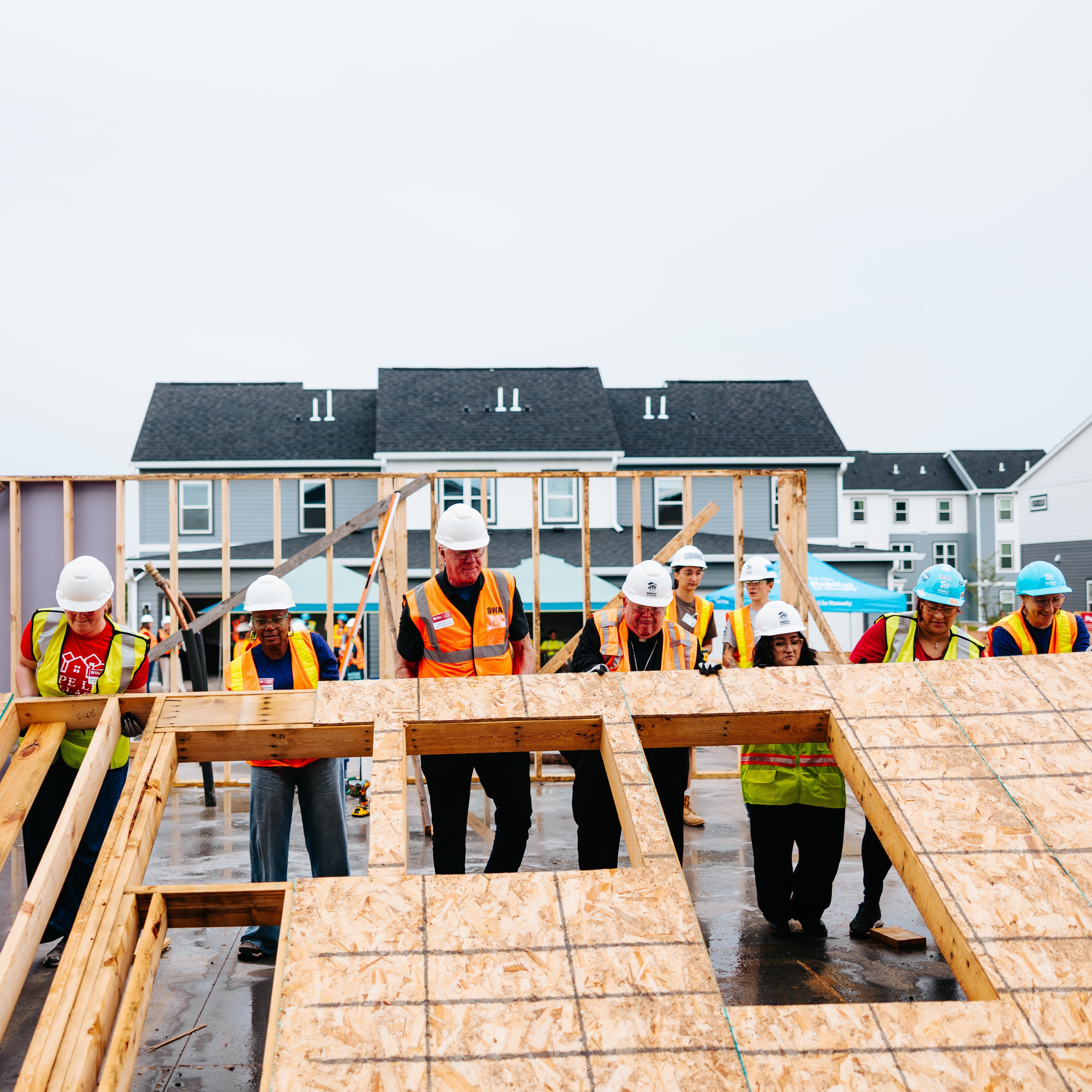 Volunteers lifting wall structure.