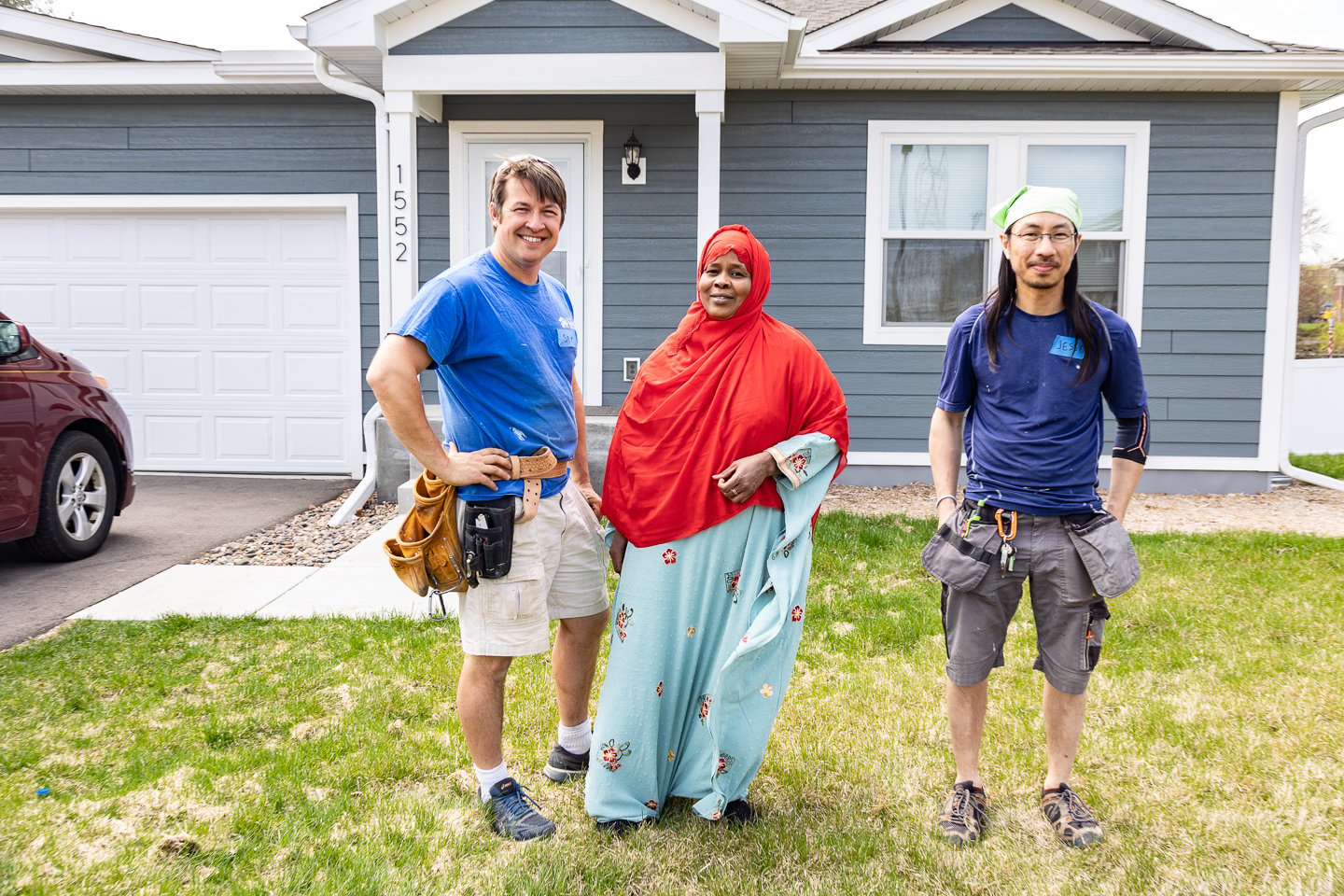 Site supervisors Skip and Jesse with Habitat homeowner Jamilo in front of her home.