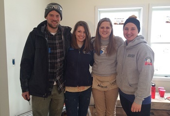 AmeriCorps members posing for a photo in an in-progress house.