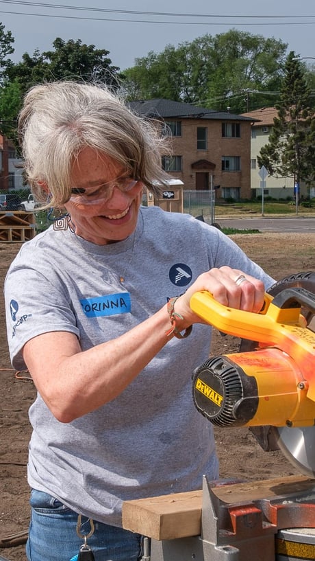 Corinna smiling while using a miter saw.