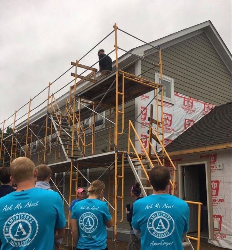 Several AmeriCorps members facing the partially-finished house they'll be working on.