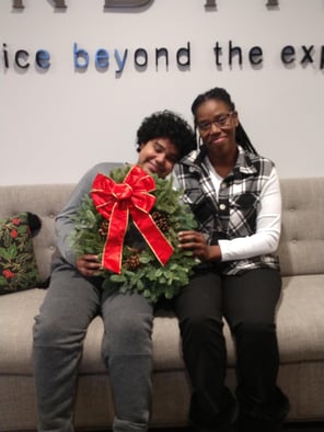Homeowner Asia and her son sitting on a couch holding a holiday wreath and smiling