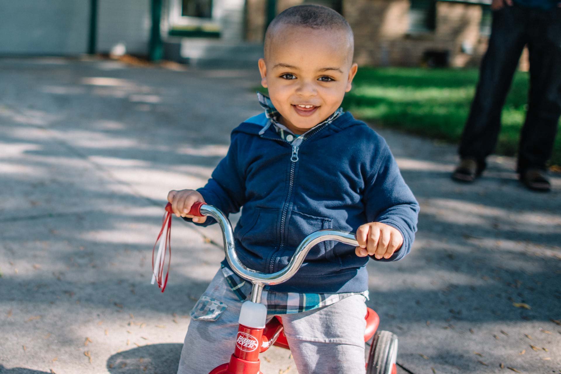 A young child smiling while riding a tricycle.