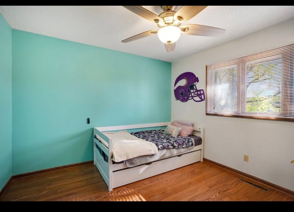 After child's bedroom with small bed and teal wall.