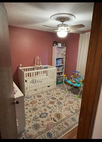 Before image of child's bedroom pink wall and crib.